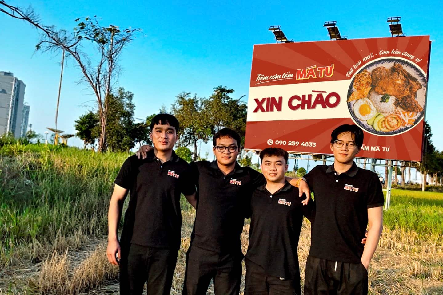 Bốn co-founder Cơm Tấm Má Tư đứng cùng nhau trước bảng hiệu vào buổi chiều